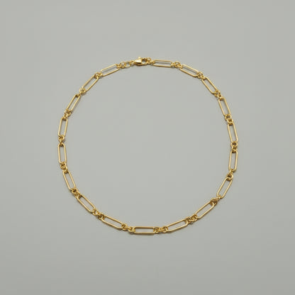 Gold chain bracelet on a gray background
