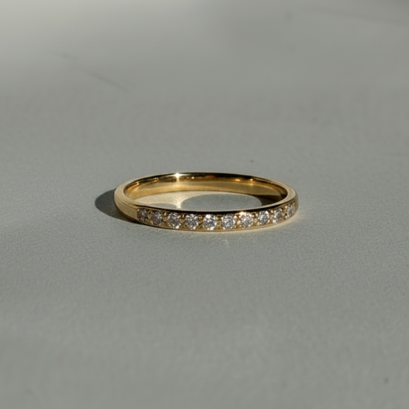 Gold ring with small diamonds on a gray background