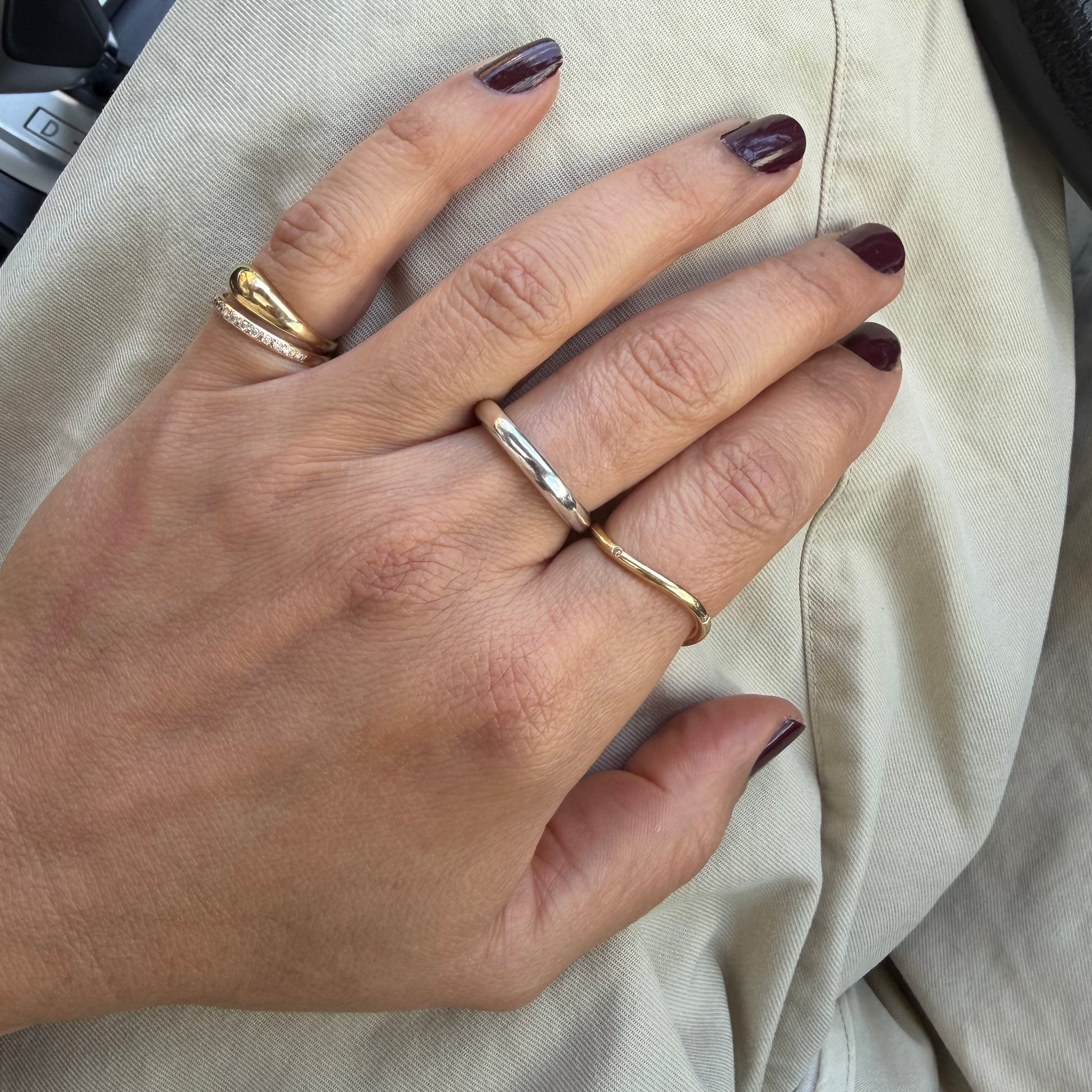Close-up of a hand wearing two gold rings with a neutral background