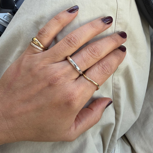 Close-up of a hand wearing two gold rings with a neutral background