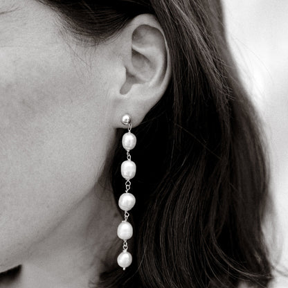 Pearl earring worn by a person with dark hair.