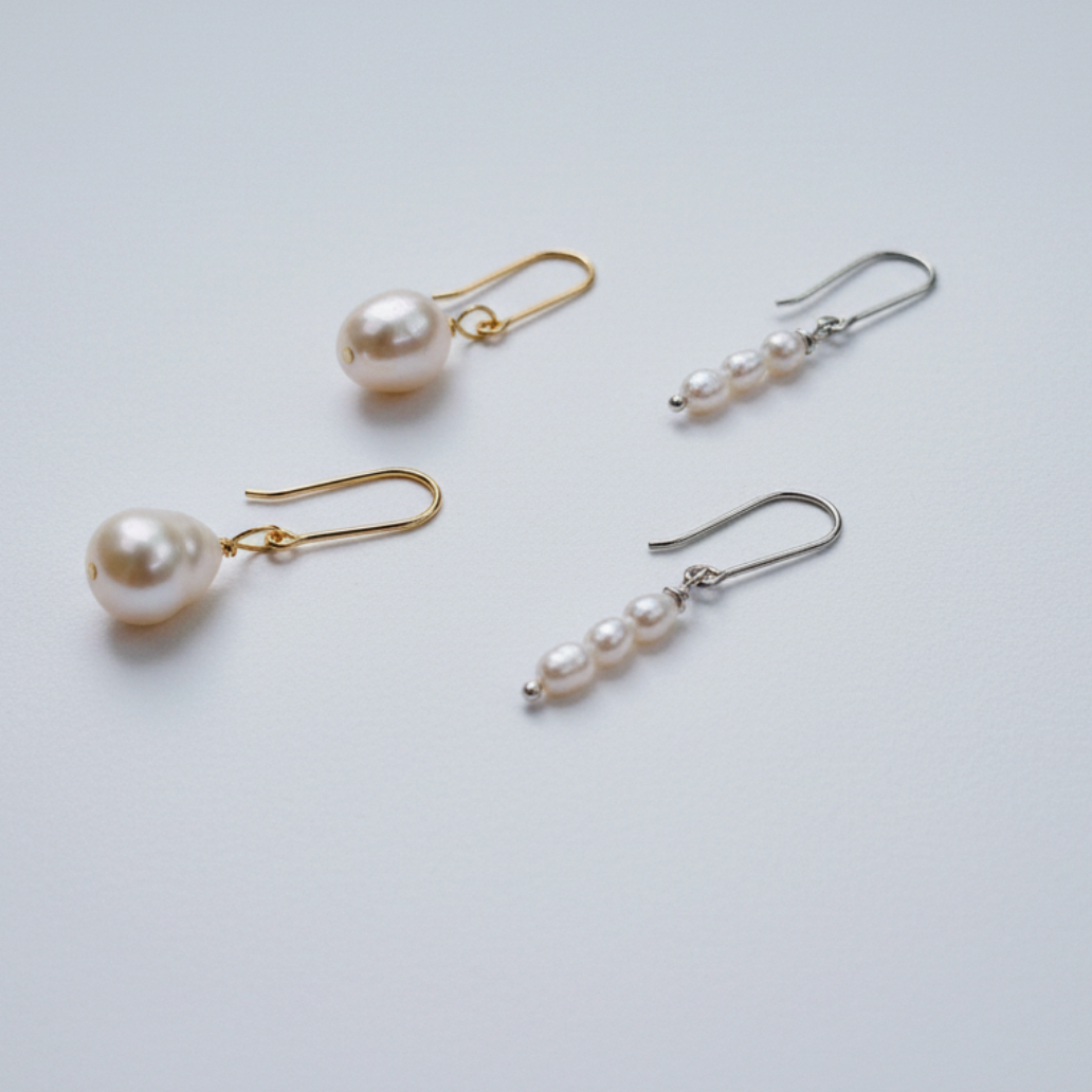 Four pairs of pearl earrings on a light gray background
