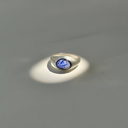 Close-up of a metallic object with a blue gem on a gray background