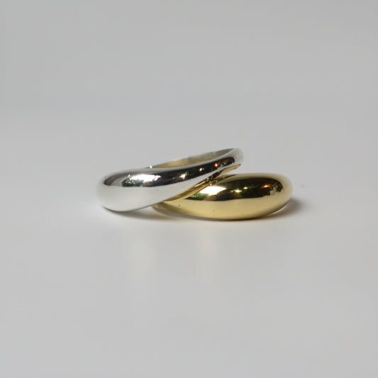 Two rings, a gold and a silver stacked on a light gray background