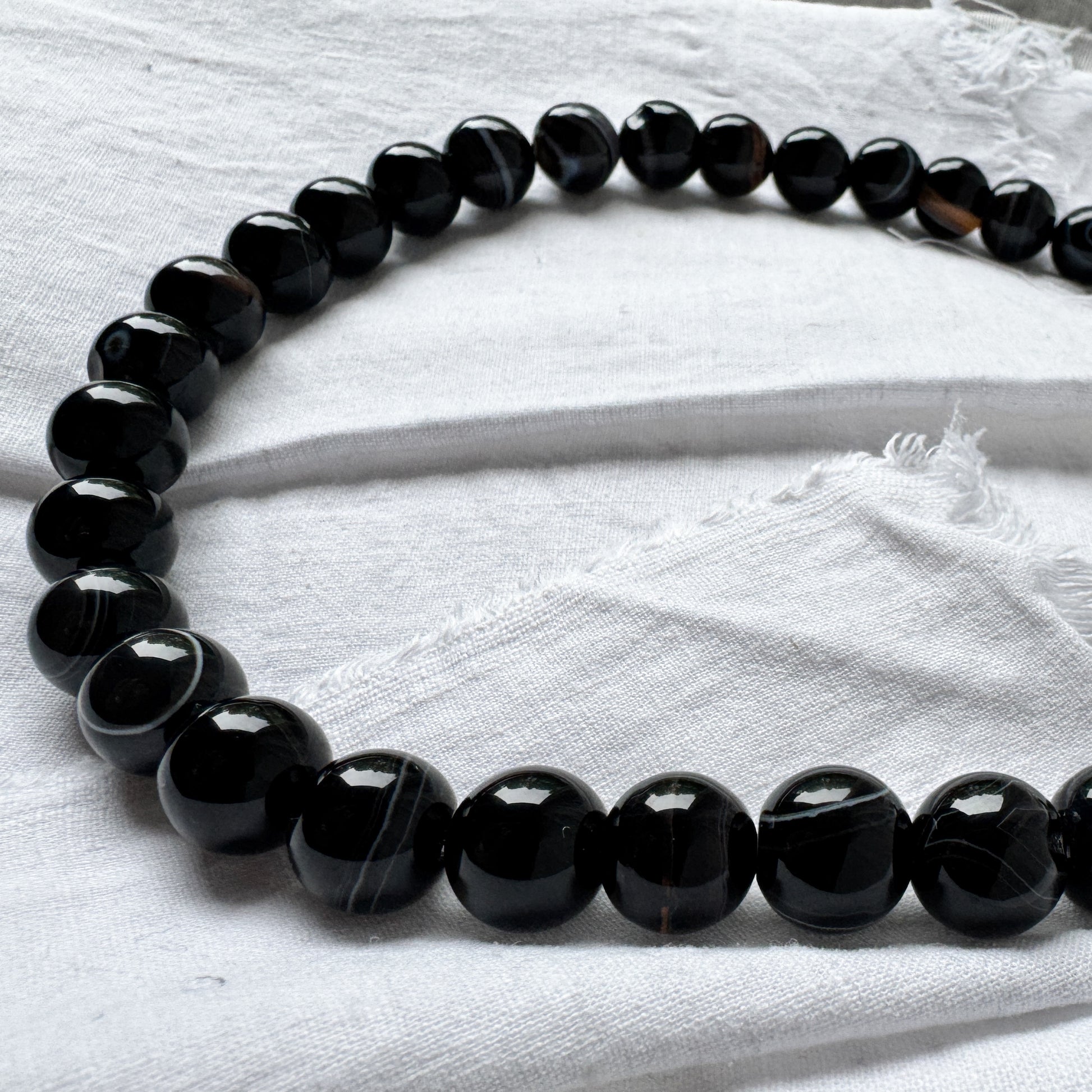 Black beaded necklace on a white fabric background