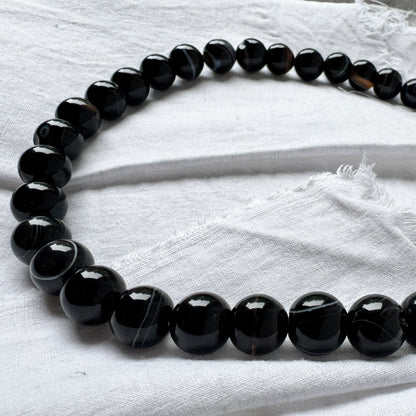 Black beaded necklace on a white fabric background