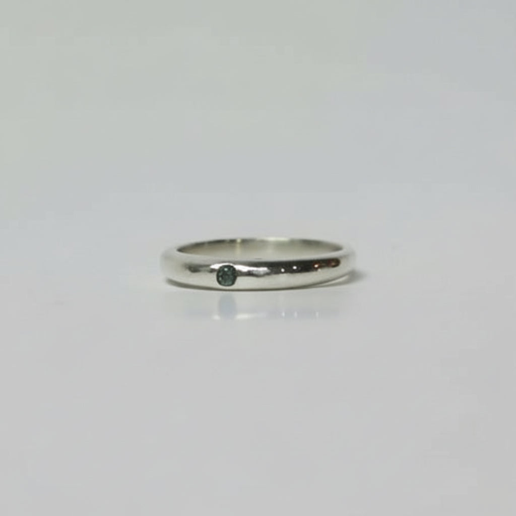 Silver ring with a small black stone on a light gray background