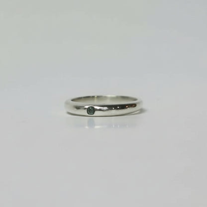 Silver ring with a small black stone on a light gray background