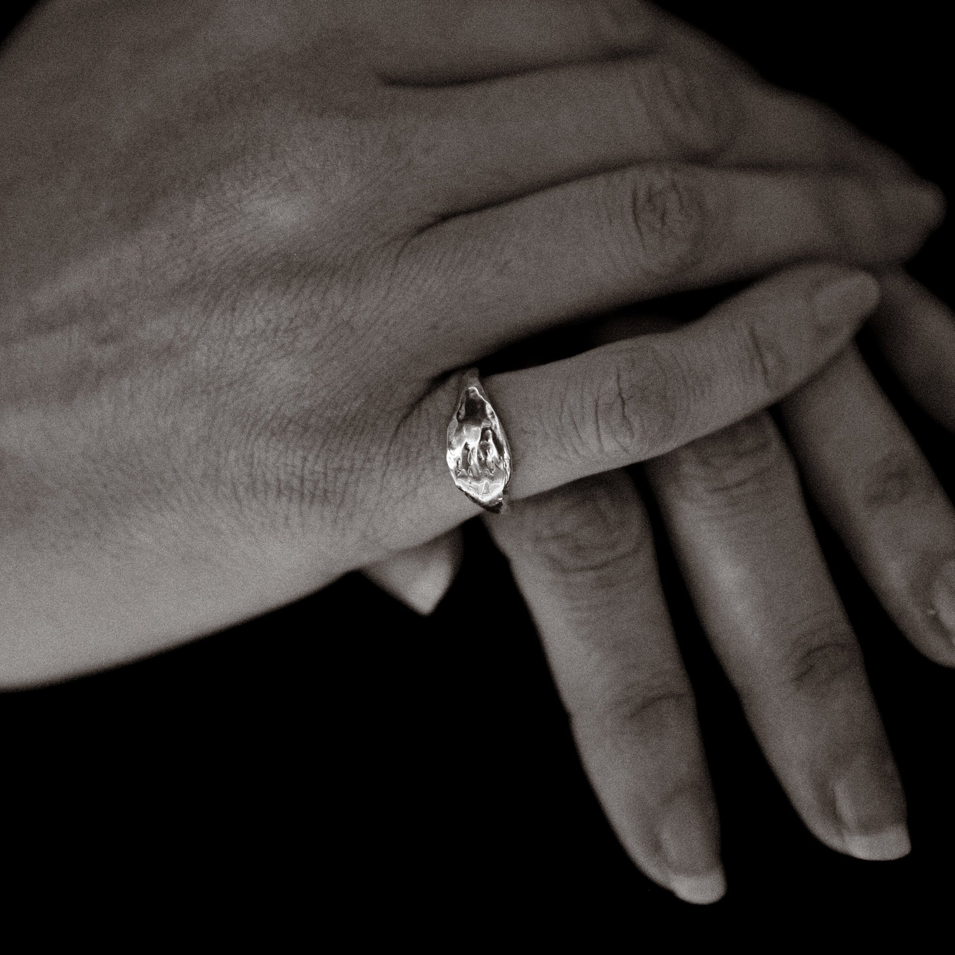 Close-up of a hand wearing a ring with a dark background