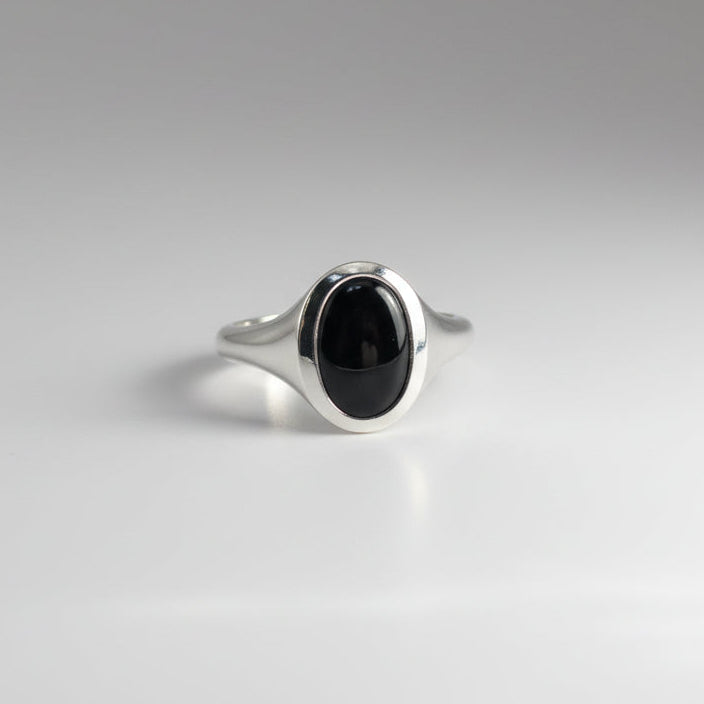 Silver ring with a black stone on a gray background