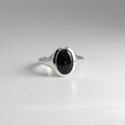 Silver ring with a black stone on a gray background