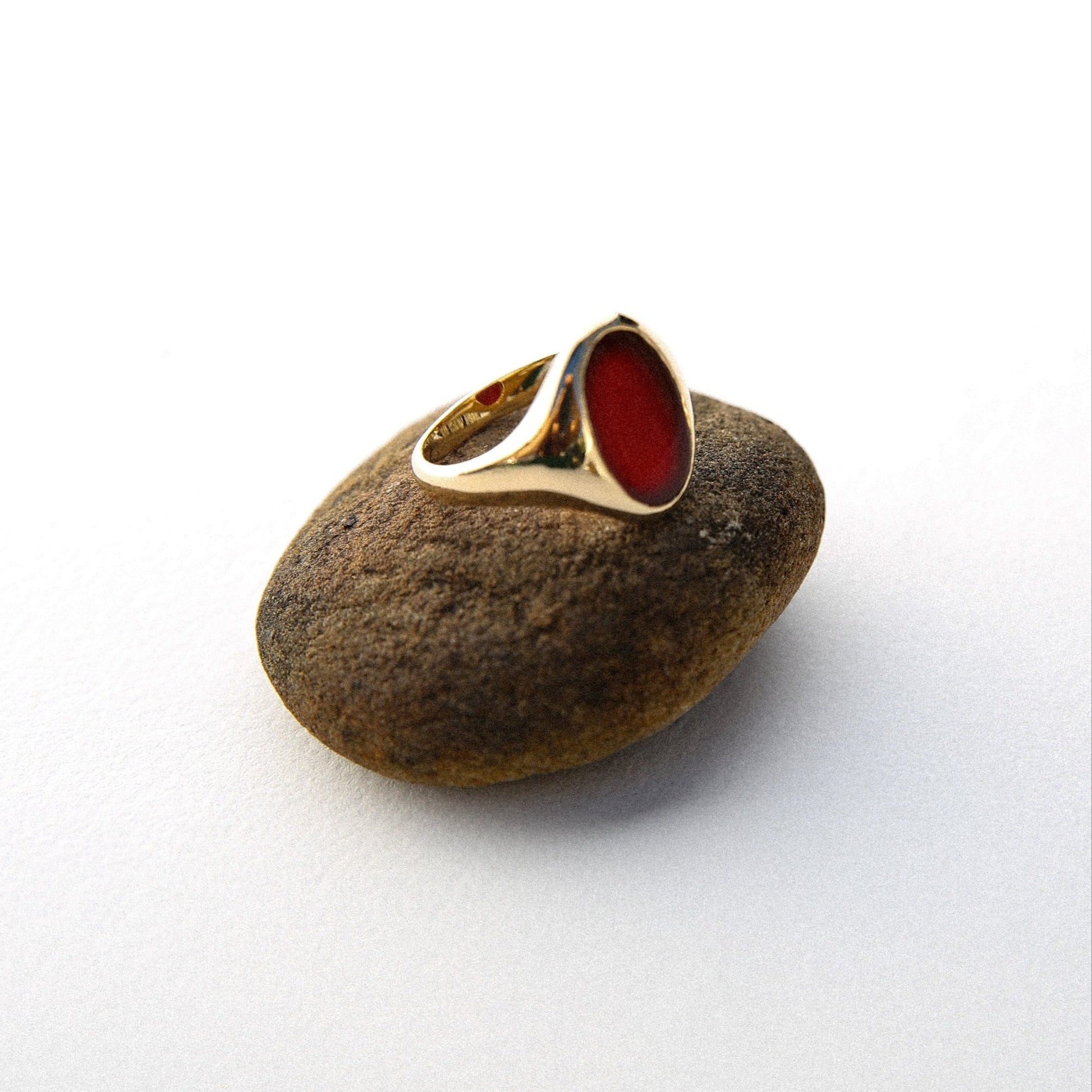 Gold ring with red stone on a textured rock