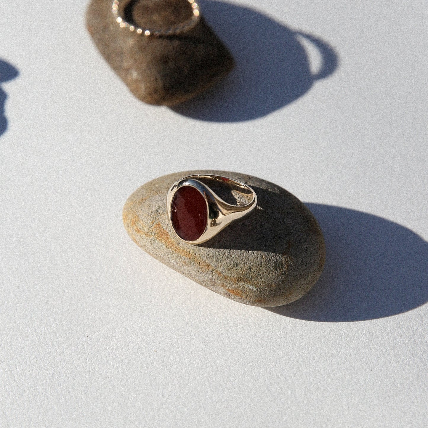 Two pebbles with embedded jewelry on a light background