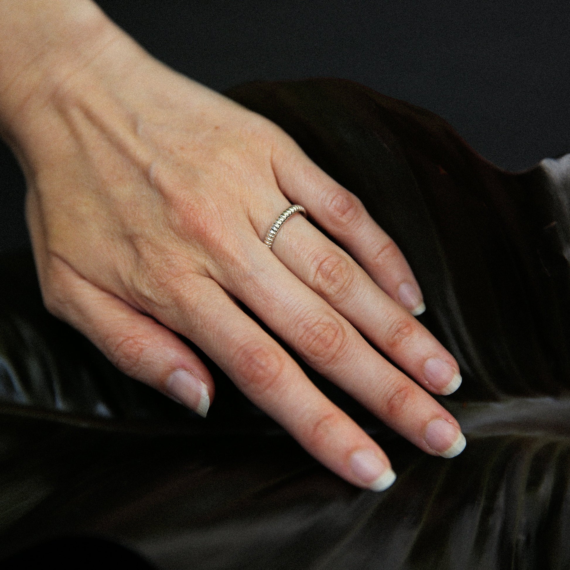 Hand with a ring on a dark surface