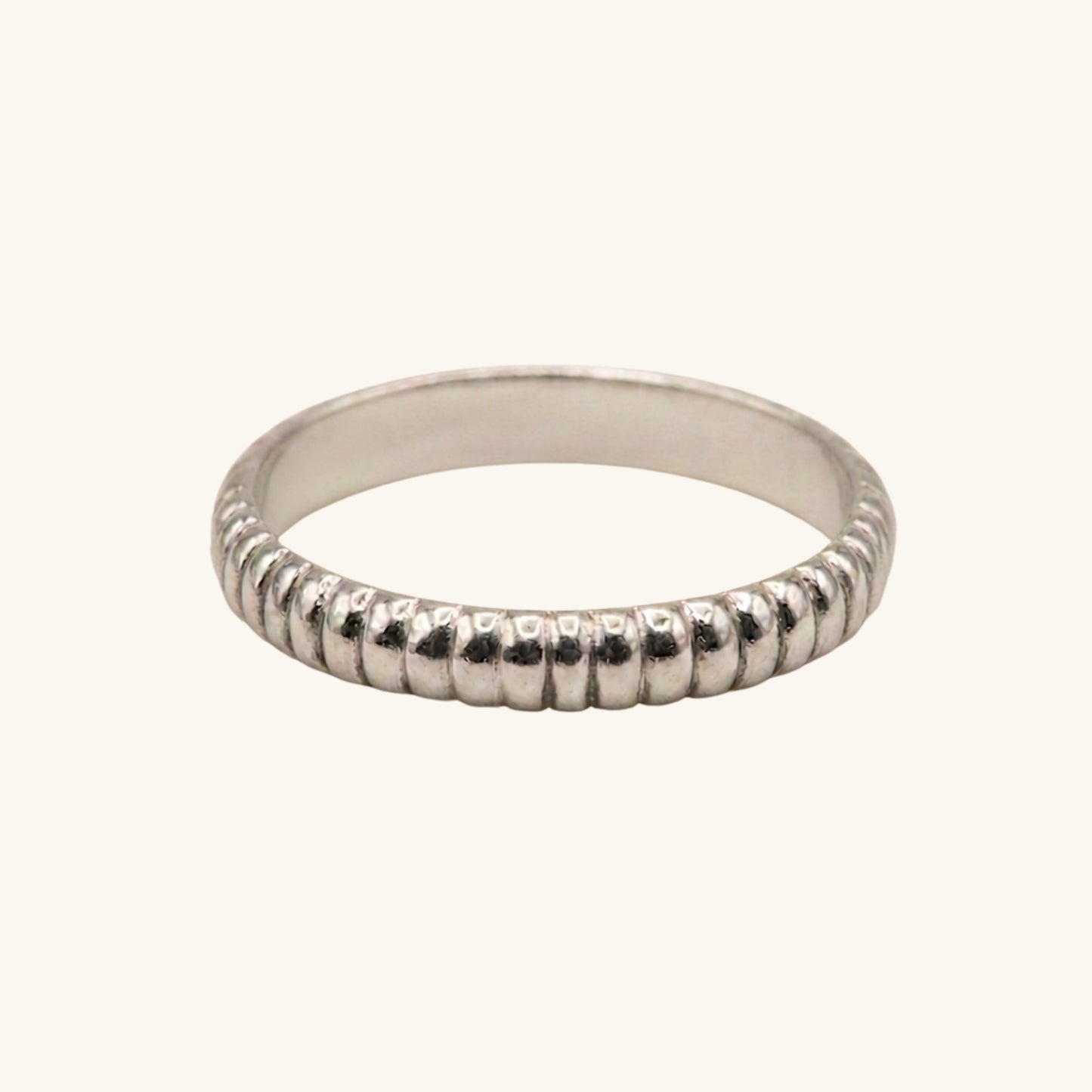 Silver ring with textured band on a white background