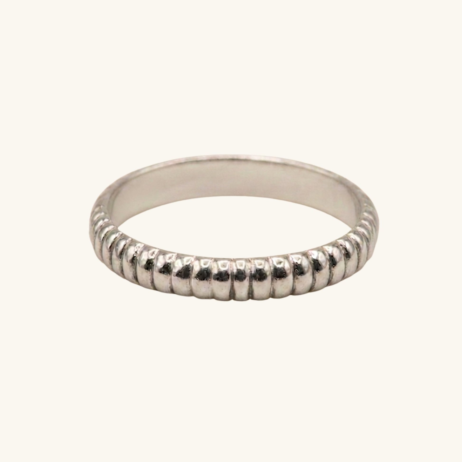 Silver ring with textured band on a white background