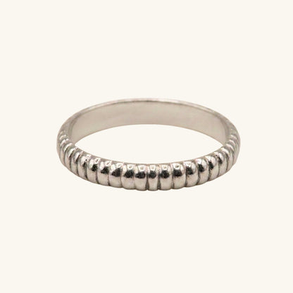 Silver ring with textured band on a white background