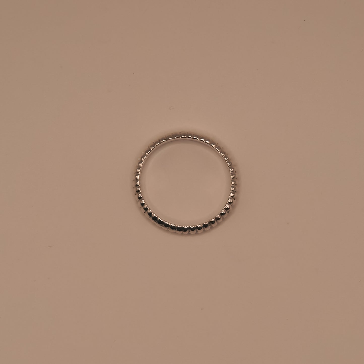 Silver ring with black beads on a beige background