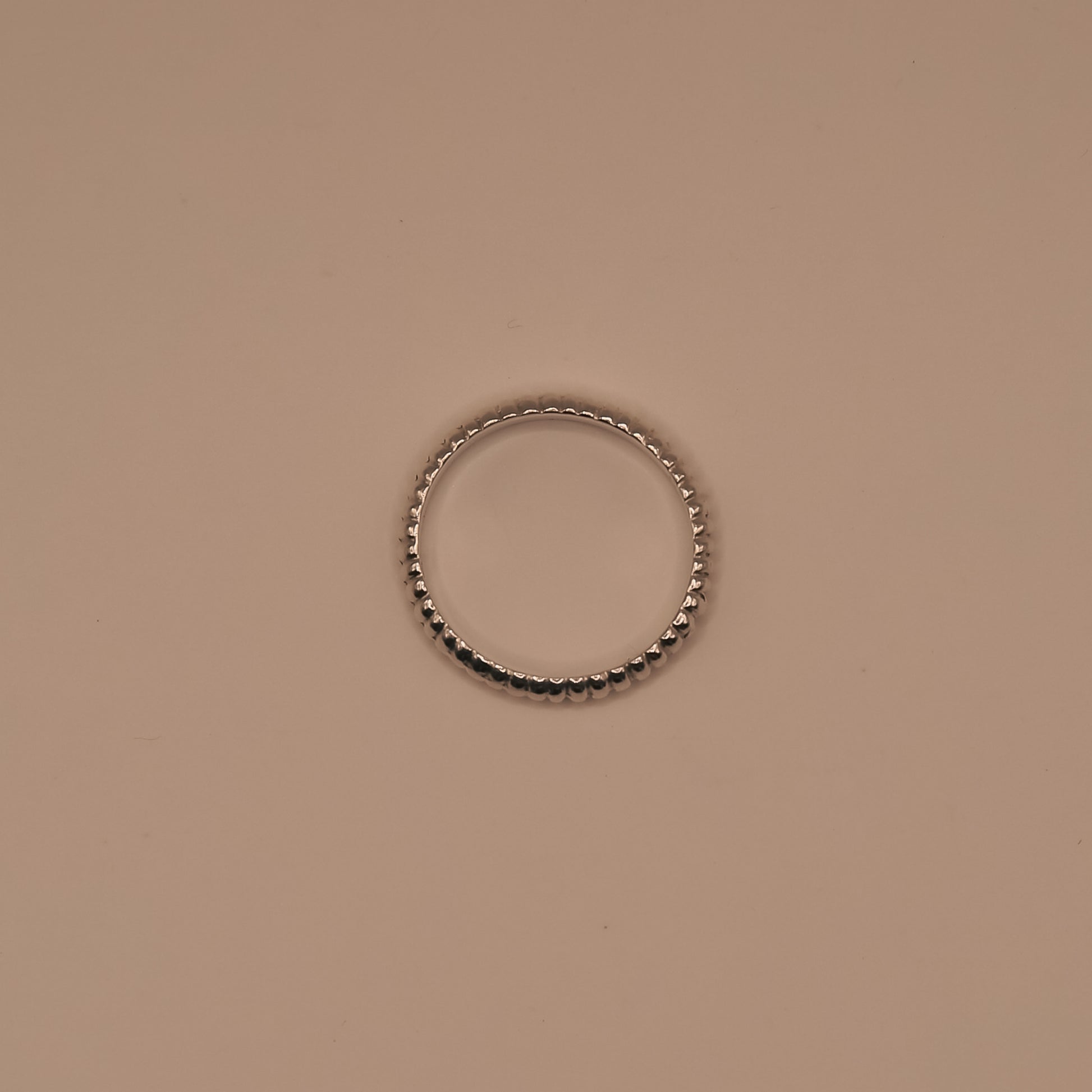 Silver ring with black beads on a beige background