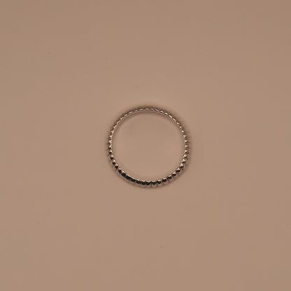 Silver ring with black beads on a beige background