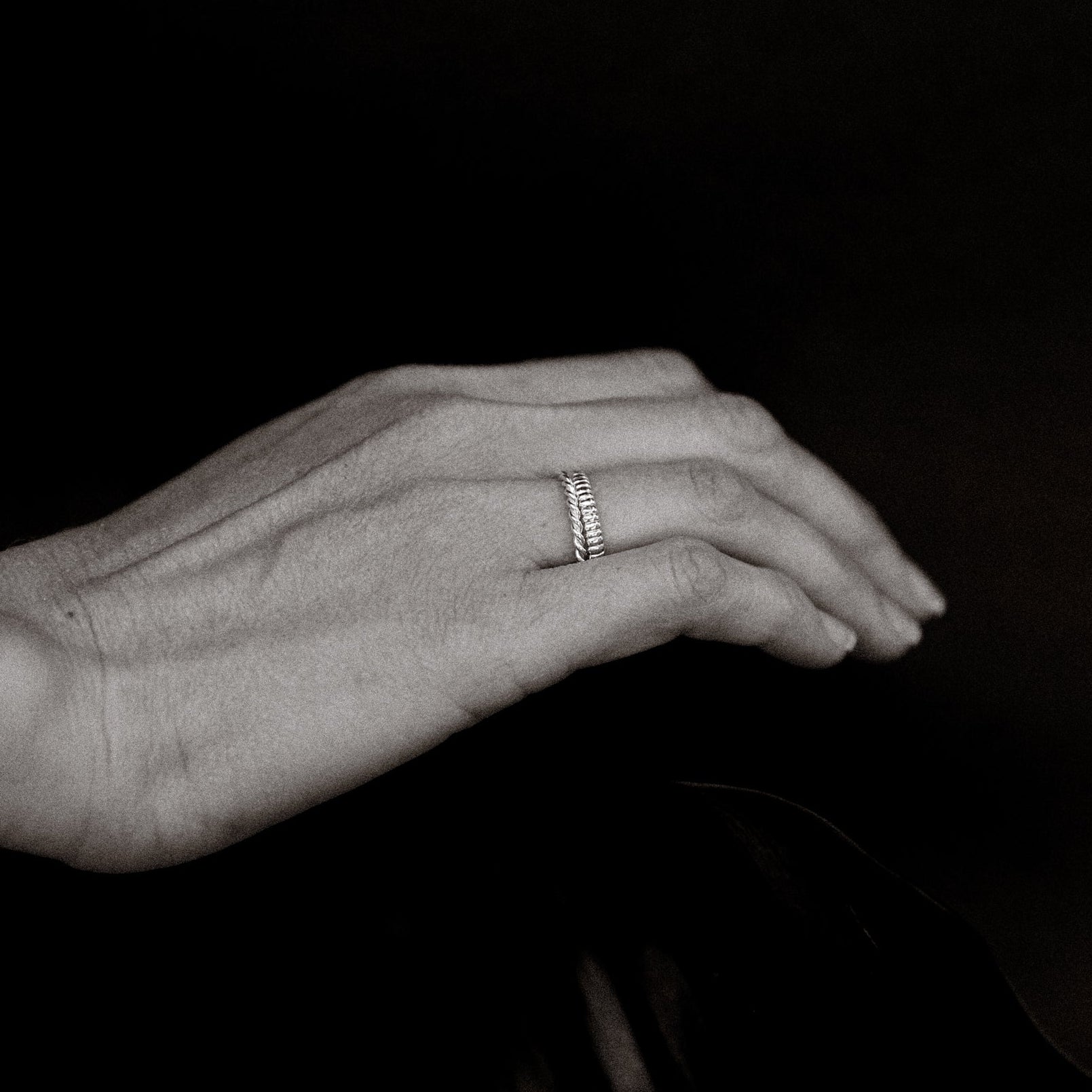 Hand wearing a ring on a black background