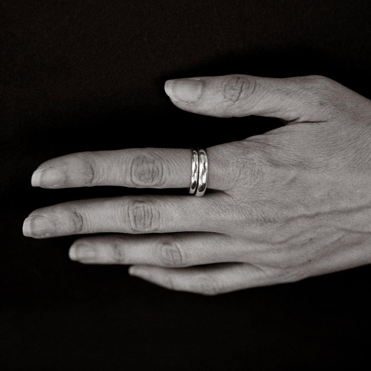 Hand with two rings on a black background