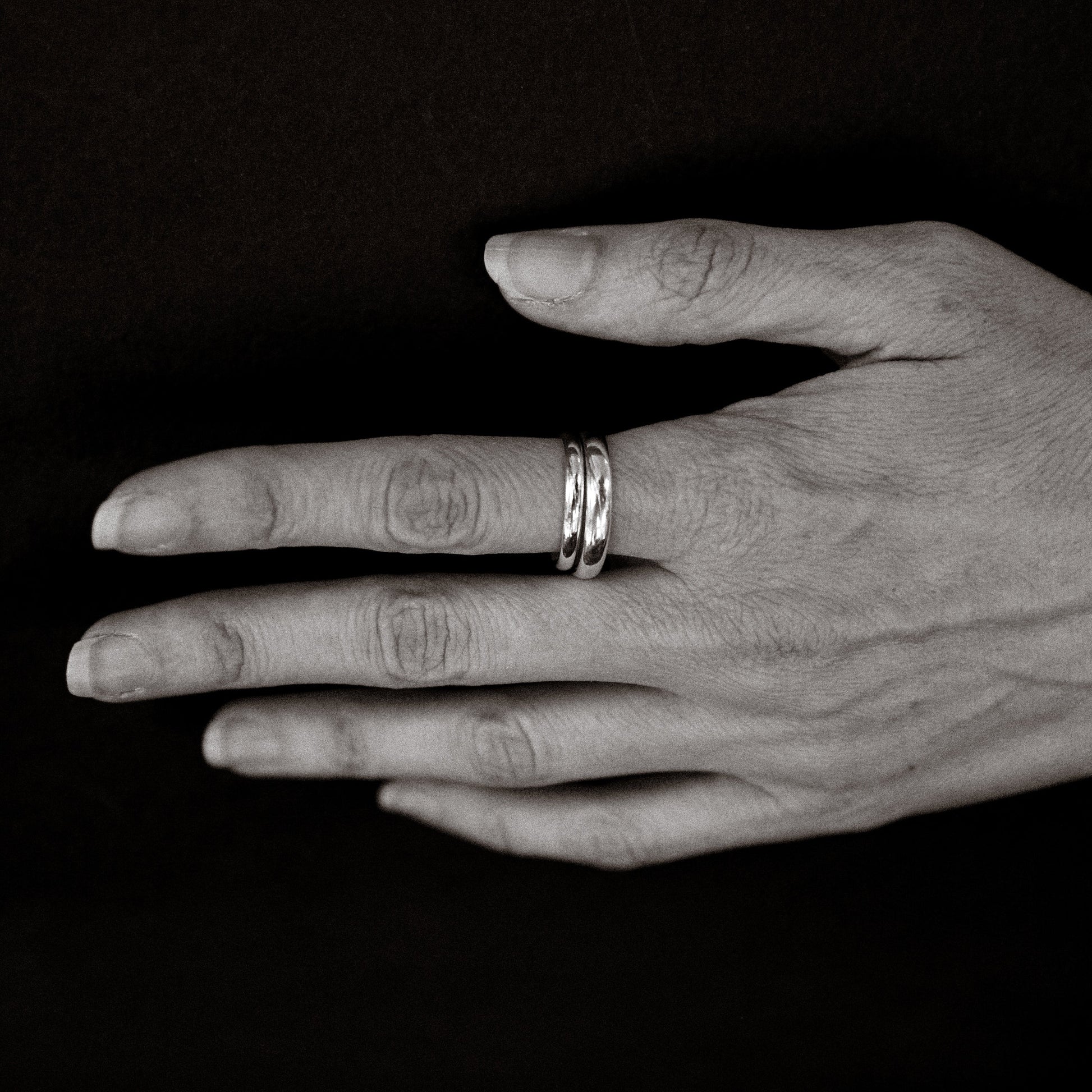 Hand with two rings on a black background