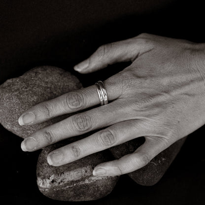 Hand holding two rocks with a ring on a dark background