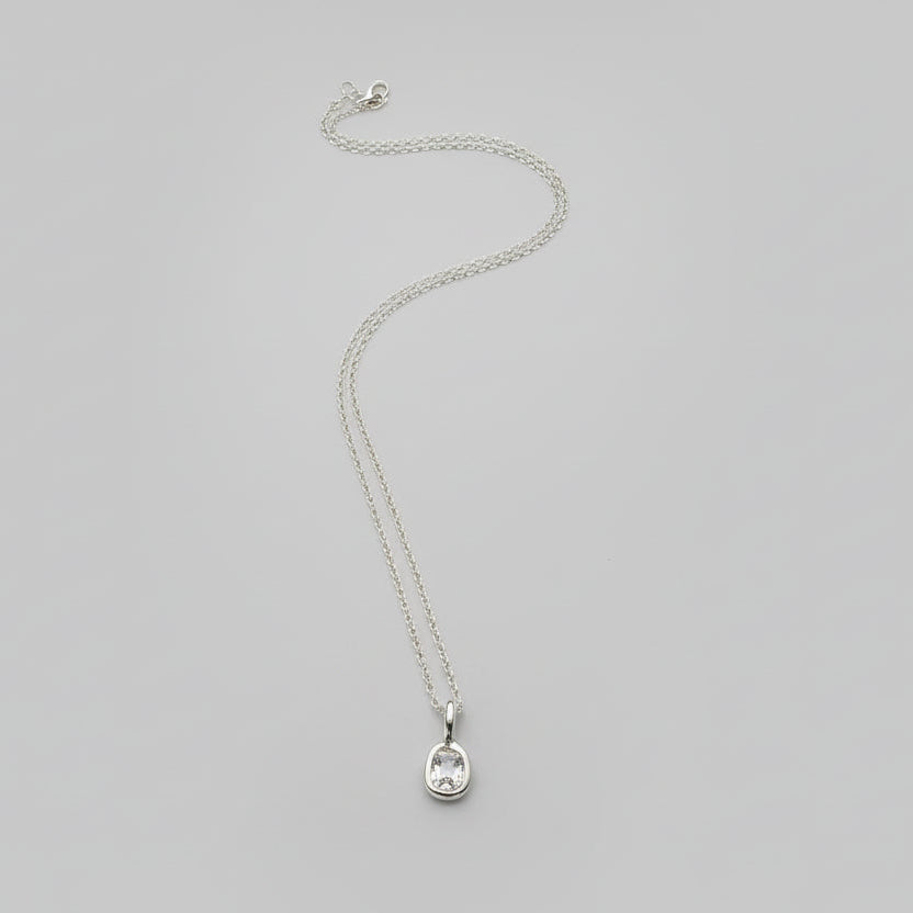 Silver necklace on a gray surface