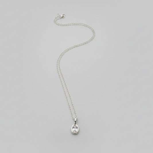 Silver necklace on a gray surface