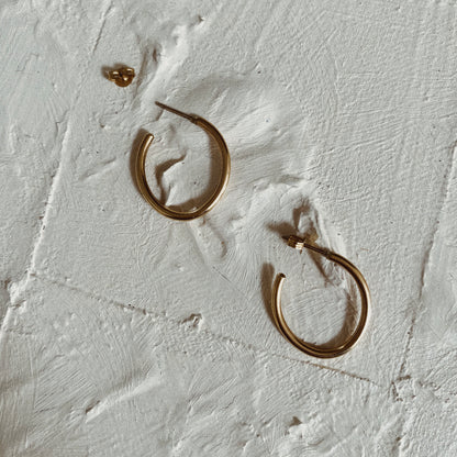 a pair of hooped gold earrings on a white textured background