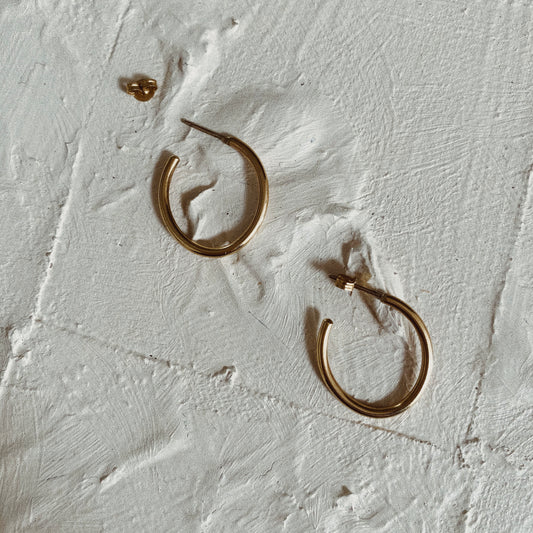 a pair of hooped gold earrings on a white textured background