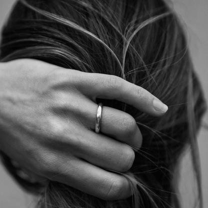 Close-up of a hand with a ring on the finger, showing a black and white photo style.