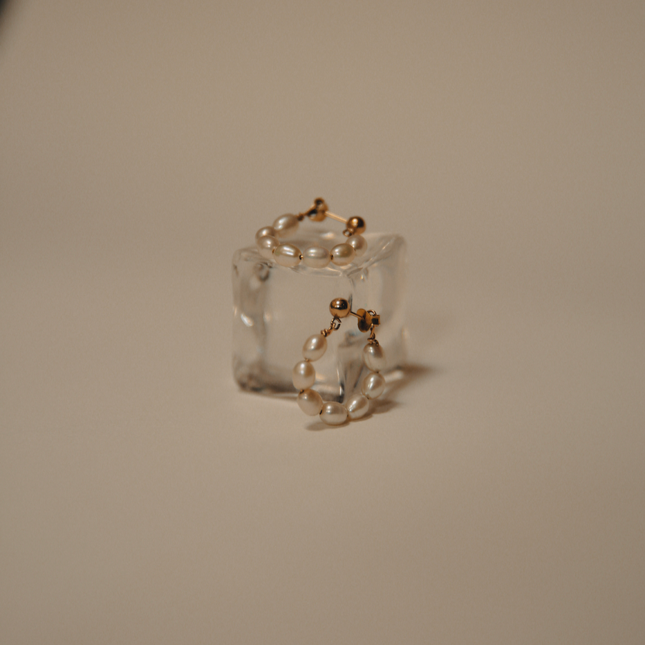 pearl hoops sitting on a resin block on a cream coloured background.