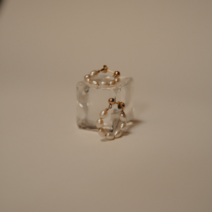 pearl hoops sitting on a resin block on a cream coloured background.
