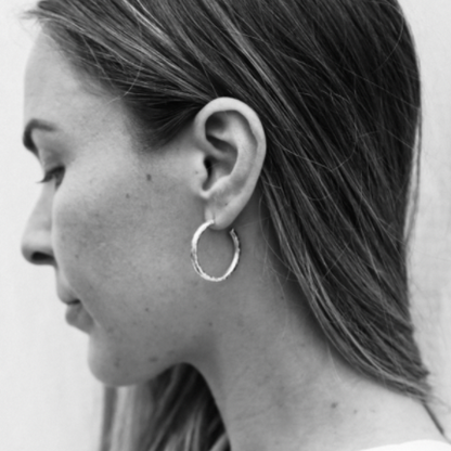 Black and white close-up of a person wearing a hoop earring.