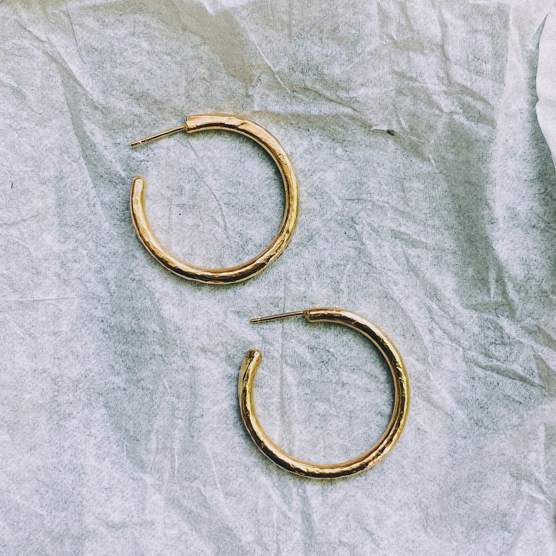 Paloma hoops in gold plate on a white crumpled background.