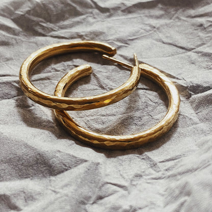 A closeup image of a pair of earrings on a crumpled white paper. 