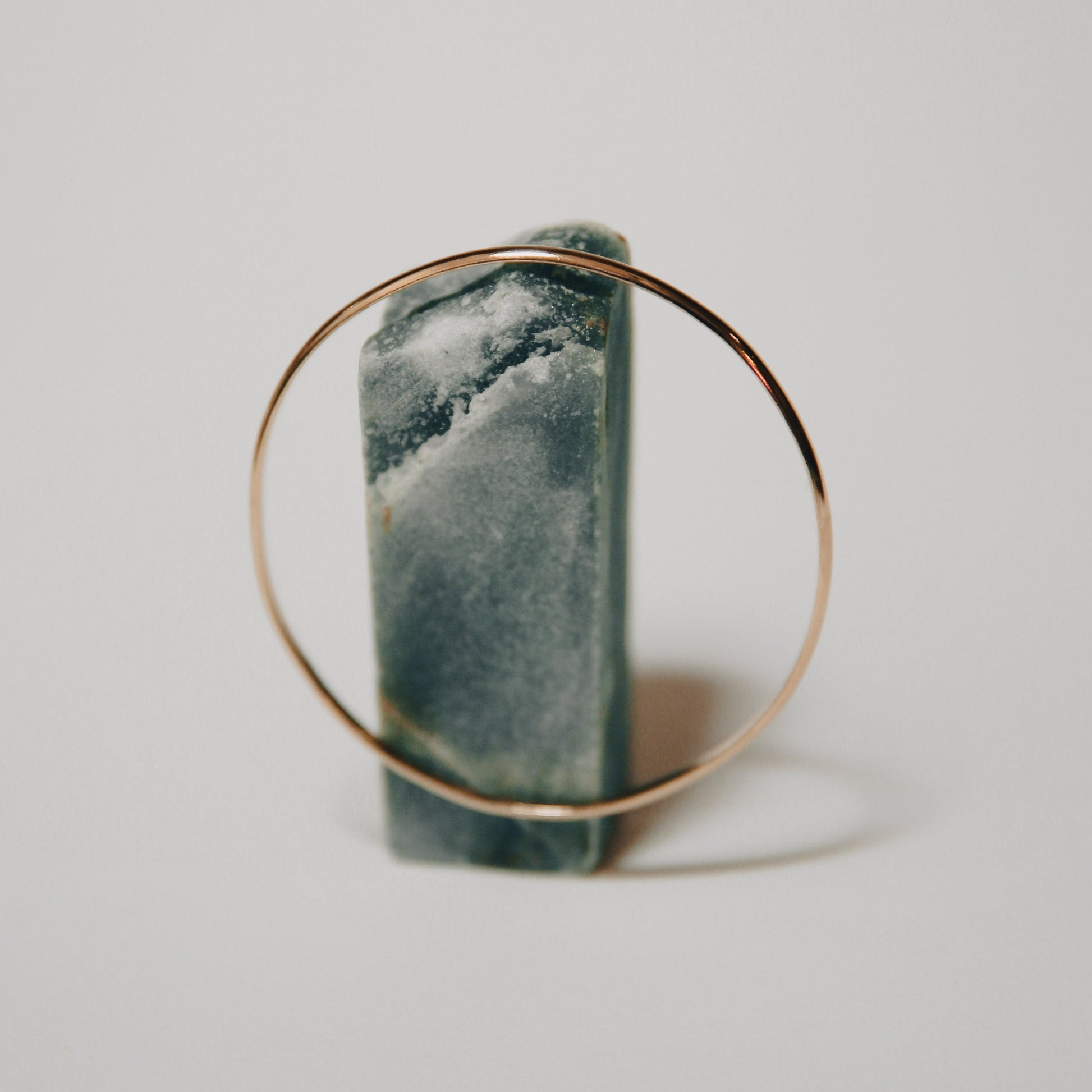 A bangle bracelet made of gold, displayed on a stand.