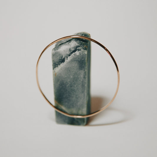 A bangle bracelet made of gold, displayed on a stand.