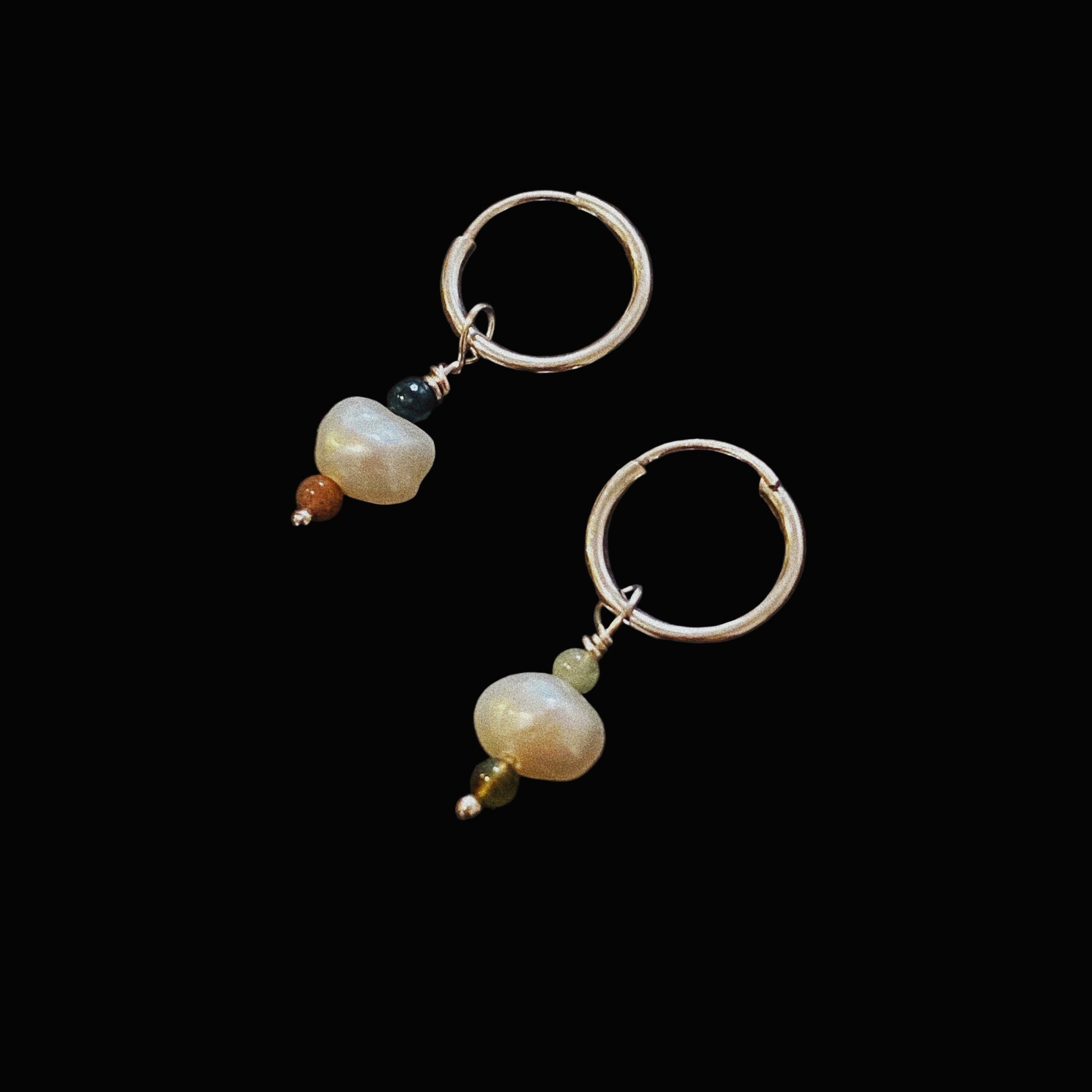 A pair of sterling silver hoop earrings with agate stones and a keishi pearl, displayed against a black background.